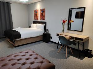 德班Durban Boutique Hotel的一间卧室配有一张床、一张书桌和一面镜子