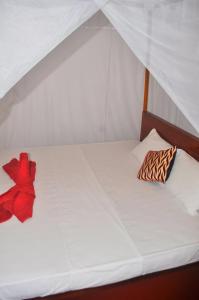 南塔拉拉Sea Breeze Inn Talalla的一张白色的床,上面有红色的弓