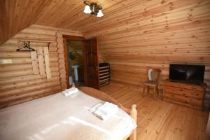 别列戈沃Садиба Арсентій的小木屋内一间卧室,配有一张床和一台电视