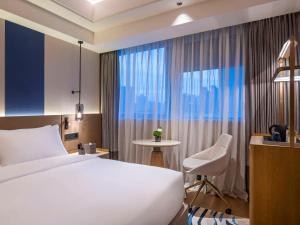 上海上海静安诺富特酒店的酒店的客房 - 带一张床、椅子和窗户