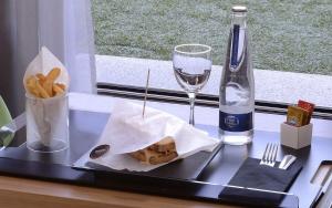 科尔多瓦科尔多瓦乌尔巴诺NH酒店的托盘,包括三明治、薯条和一瓶葡萄酒