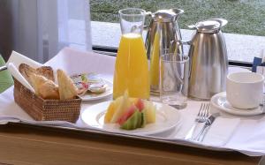 科尔多瓦科尔多瓦乌尔巴诺NH酒店的托盘,包括两盘面包、果汁和烤面包