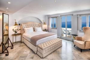 费拉雅典娜豪华套房酒店的一间卧室配有一张大床和一把椅子