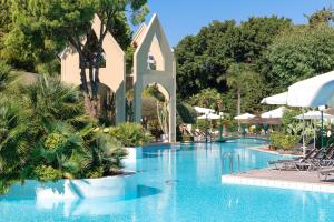 依克希亚迪俄尼索斯酒店的度假村的游泳池,配有椅子和遮阳伞