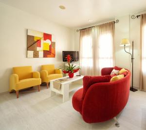 阿尔卡拉拉雷亚尔托瑞帕玛酒店的客厅配有红色沙发和2把黄色椅子