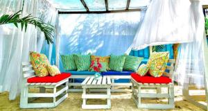 El CharquitoSummer beach hotel的蓝色的沙发,配有色彩缤纷的枕头和两把椅子