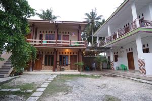 比哈尔Sapu Nyapah Losmen Syariah Tanjung Setia的一座大房子前面设有一个庭院