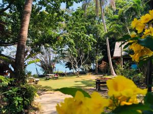 阁遥岛Sabai Corner Bungalows - SHA Extra Plus的公园里设有野餐桌,种有树木和黄色的花朵