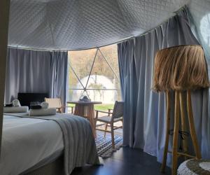 卡洛帕尼亚伊奥蒂斯River Glamping Kalopanayiotis的一间卧室设有一张床和一个大窗户