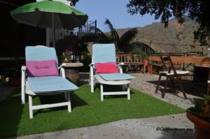 埃尔米瓜Casa rural con Wifi y estupenda vista a la montaña en Hermigua的两把椅子坐在草地上,一把伞