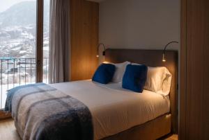 埃尔塔特ISARD RESIDENCES & SPA by Elegant Residences的一间卧室配有一张带蓝色枕头的床和一扇窗户。