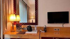 迪拜Dubai Grand Hotel by Fortune, Dubai Airport的酒店客房设有一张桌子,墙上配有电视。