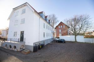 奥尔堡aday - 3 bedroom - Modern Living Apartment - Aalborg Center的旁边设有停车场的白色房子