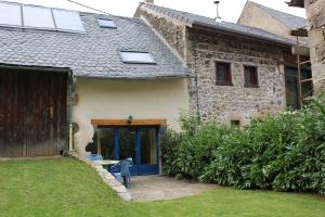 CeyssatAu coeur des Volcans d'Auvergne的一座石头房子,有蓝色的门和院子
