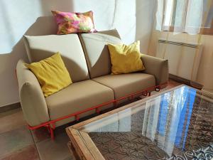 马赛Petit cocon à Mourepiane的一张带黄色枕头的沙发和玻璃桌