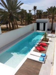Al MaqārisahVilla Oasis de Luxe avec Piscine et Vue Panoramique的游泳池设有红色和蓝色的椅子,棕榈树