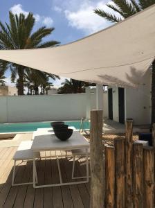 Al MaqārisahVilla Oasis de Luxe avec Piscine et Vue Panoramique的游泳池畔的一张桌子上边的白色遮阳伞