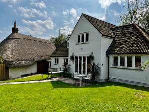 Sutton BengerSpinners House, rural home on edge of Cotswolds的白色的房子,有茅草屋顶和院子