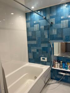 ゲストハウスみんちゅう的浴室设有浴缸,铺有蓝色瓷砖。