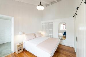 拉日什杜皮库Engenho Hostel的白色卧室配有床和镜子