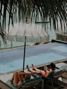 蓝梦岛极光海滩景旅馆的两人躺在游泳池旁的躺椅上