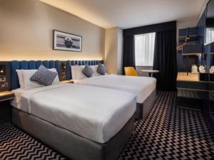 都柏林学院广场酒店的酒店客房设有两张床和一张桌子。