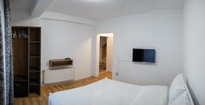 斯特鲁加Hotel Lux的白色的房间,设有床铺和墙上的电视
