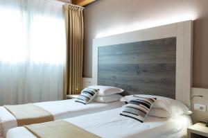 梅斯特亚历山大酒店 的配有木床头板的酒店客房内的两张床