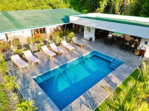 PlatanilloParadiselodge Jungleguesthouse的享有带椅子的游泳池和房屋的顶部景致
