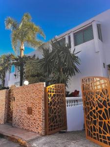 卡萨布兰卡Nassali - Luxurious Beachfront Villa with Private Pool的白色的房子,有栅栏和棕榈树