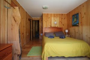 库拉考廷Hotel Lodge Fundo Laguna Blanca的一间卧室设有黄色的床和木墙