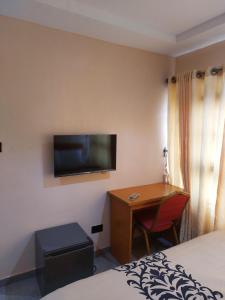 OjoDopad Hills Hotel and Suites的酒店客房设有一张桌子和一台墙上的电视