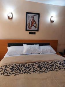 OjoDopad Hills Hotel and Suites的卧室内的一张床铺,墙上挂着一幅画