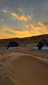 BadīyahMarbella bungalows desert的日落时分沙漠中两座小屋