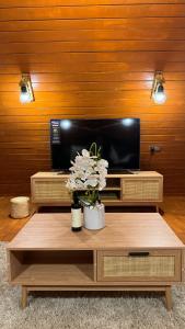 BadīyahMarbella bungalows desert的客厅配有电视和鲜花桌