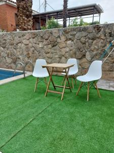 马德里Apartamento cercano a IFEMA, Aeropuerto, Clinica Universitaria Navarra y Civitas Metropolitano的游泳池旁的草地上摆放着三把椅子和一张木桌
