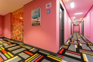 圣保罗圣保罗巴拉芬达宜必思尚品酒店的走廊设有粉红色的墙壁和色彩缤纷的地板