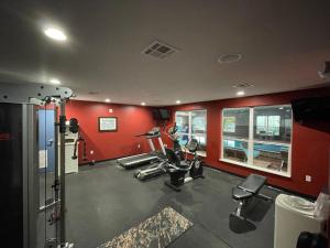 什里夫波特Del-Mar Airport Inn & Suites的一间设有红色墙壁和跑步机的健身房