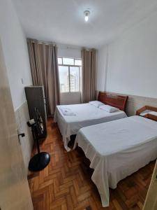 贝洛奥里藏特Comodidade e Segurança no Centro的酒店客房设有两张床和窗户。