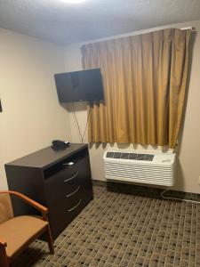 阿什塔比拉Economy Inn & Suites的客房设有椅子、书桌和窗户。