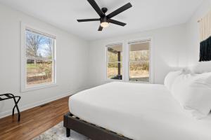 阿什维尔Sage Lodge by AvantStay 15 Min to Downtown Deck的白色卧室设有吊扇和窗户。