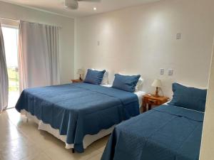 康赛瓦托利亚Pousada Alto da Serra的一间卧室设有两张带蓝色床单的床和窗户。
