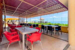 坎昆Apartamento en complejo hotelero con playa的一间设有红色桌椅的海洋餐厅
