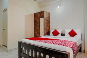 班加罗尔Oyo Flagship Sri Chowdeshwari Boarding And Lodging的一间卧室配有一张带红色枕头的大床