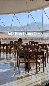瓦迪拉姆Julia Rum Luxury Camp的坐在餐厅桌子上的男人