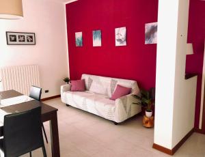 阿斯蒂la Dolce Vita - Appartamento con parcheggio privato vicino al centro e all'ospedale的客厅配有白色沙发和红色墙壁