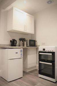 约克Priory Studio- New apartment inside the city walls的厨房配有白色橱柜和黑烤箱。