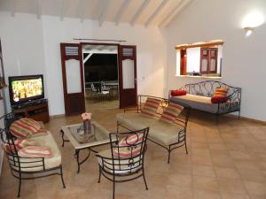 拜马欧Villa Magnifique piscine & jardin的客厅配有沙发、椅子和电视