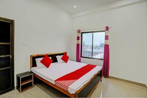 瓦拉纳西OYO Flagship Hotel Bhardwaj的一间卧室配有一张带红色枕头的床和一扇窗户