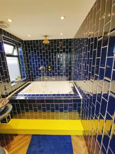 伦敦Jacuzzi Suite的带浴缸的浴室和蓝色瓷砖墙壁
